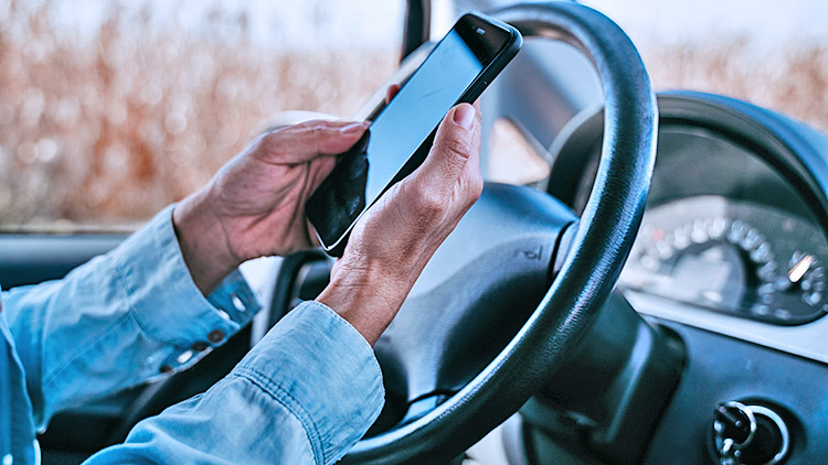 Hands checking mobile phone in drivers seat of car