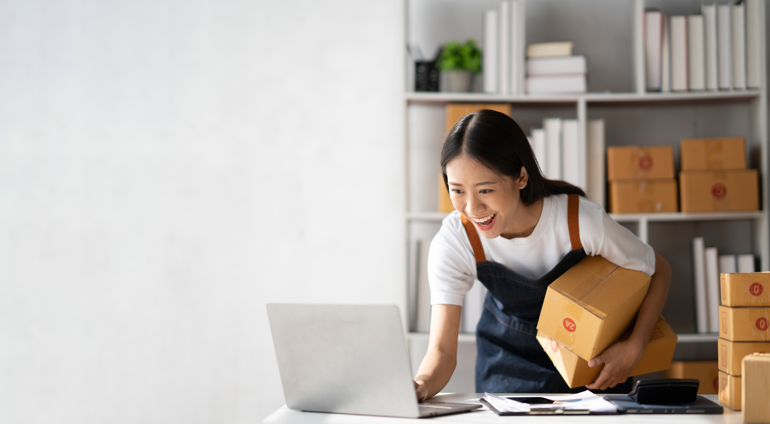 This new business owner holds a shipment while checking her laptop. Be sure to invest time and effort in choosing a business name that resonates with your target audience and reflects your brand values. 