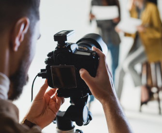 Man standing behind a professional camera setting up a photoshoot with two women after getting his business license thought LegalZoom.