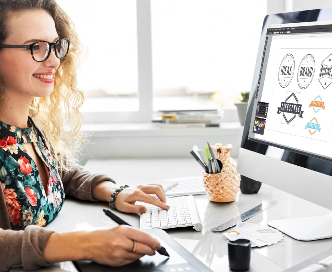 Woman’s hands working at a desk sitting in front of a computer creating a logo that will be trademarked with LegalZoom.